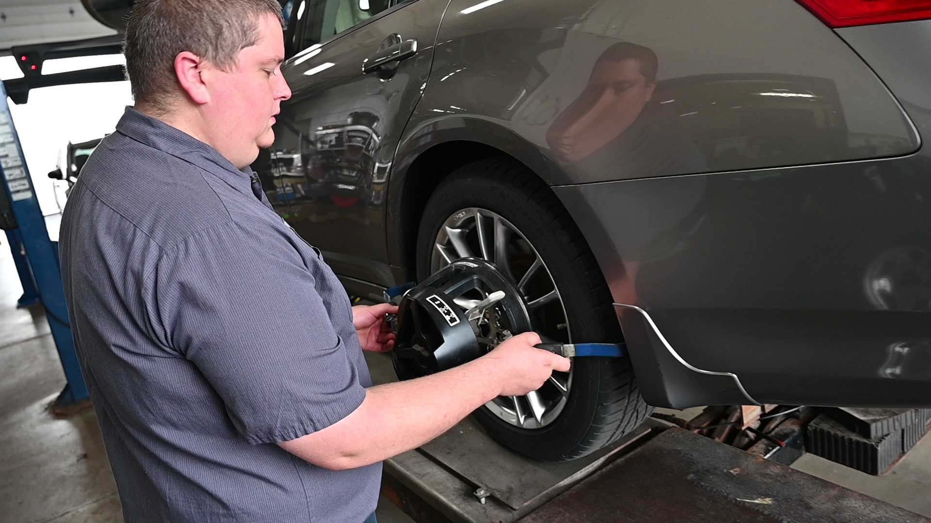 Technician attaching alignment sensor while performing a wheel alignment in Menasha, WI