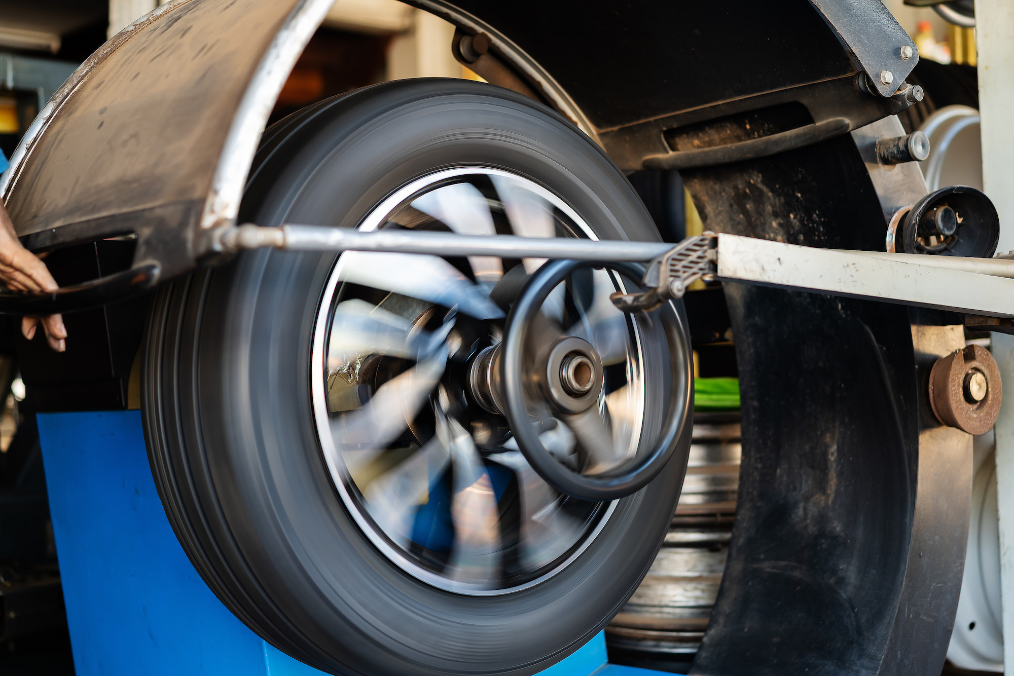 Spinning car wheel on tire balancing machine during service at auto shop in Green Bay, WI.