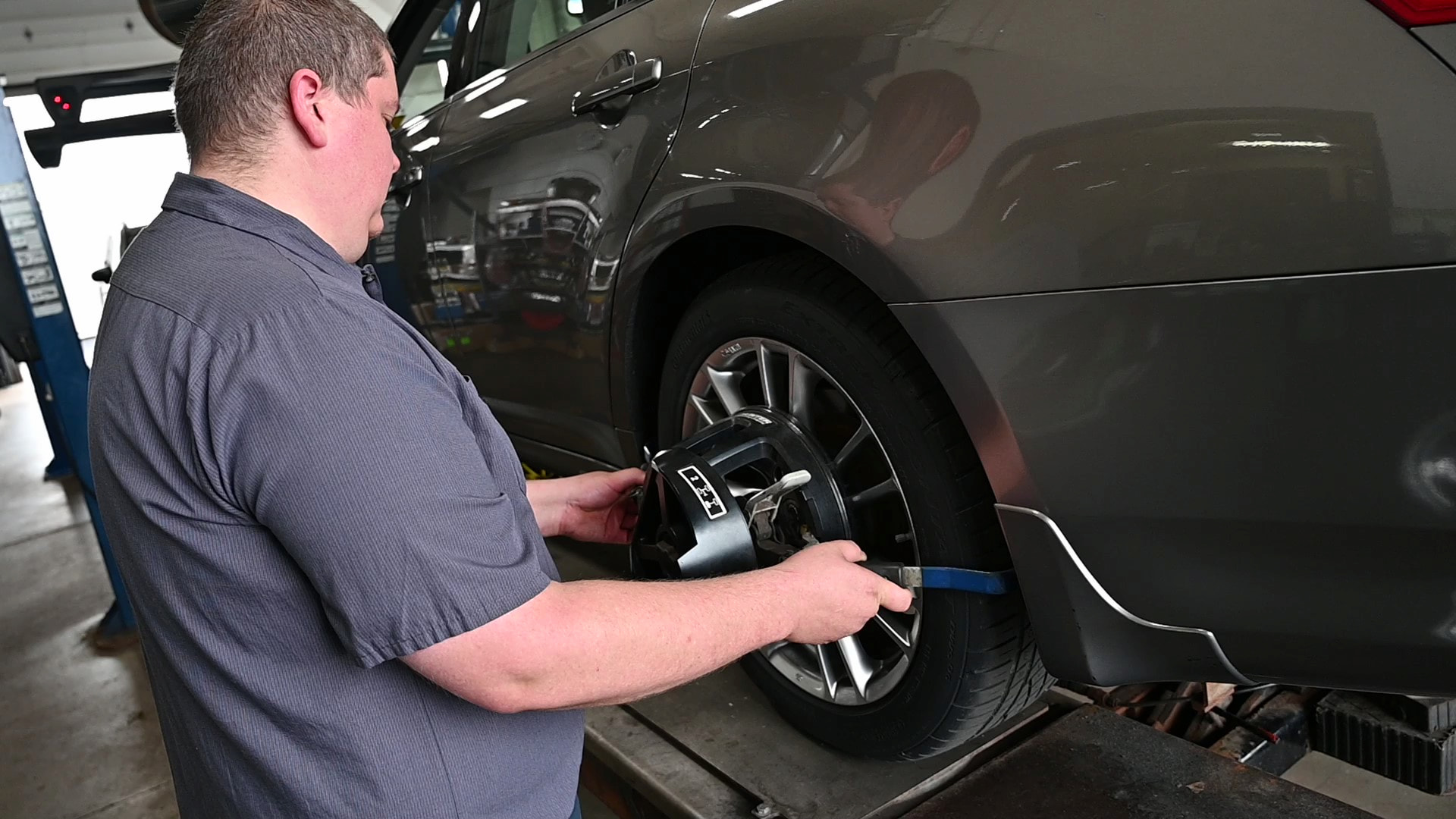 Technician attaching alignment sensor while performing a wheel alignment in Green Bay, WI