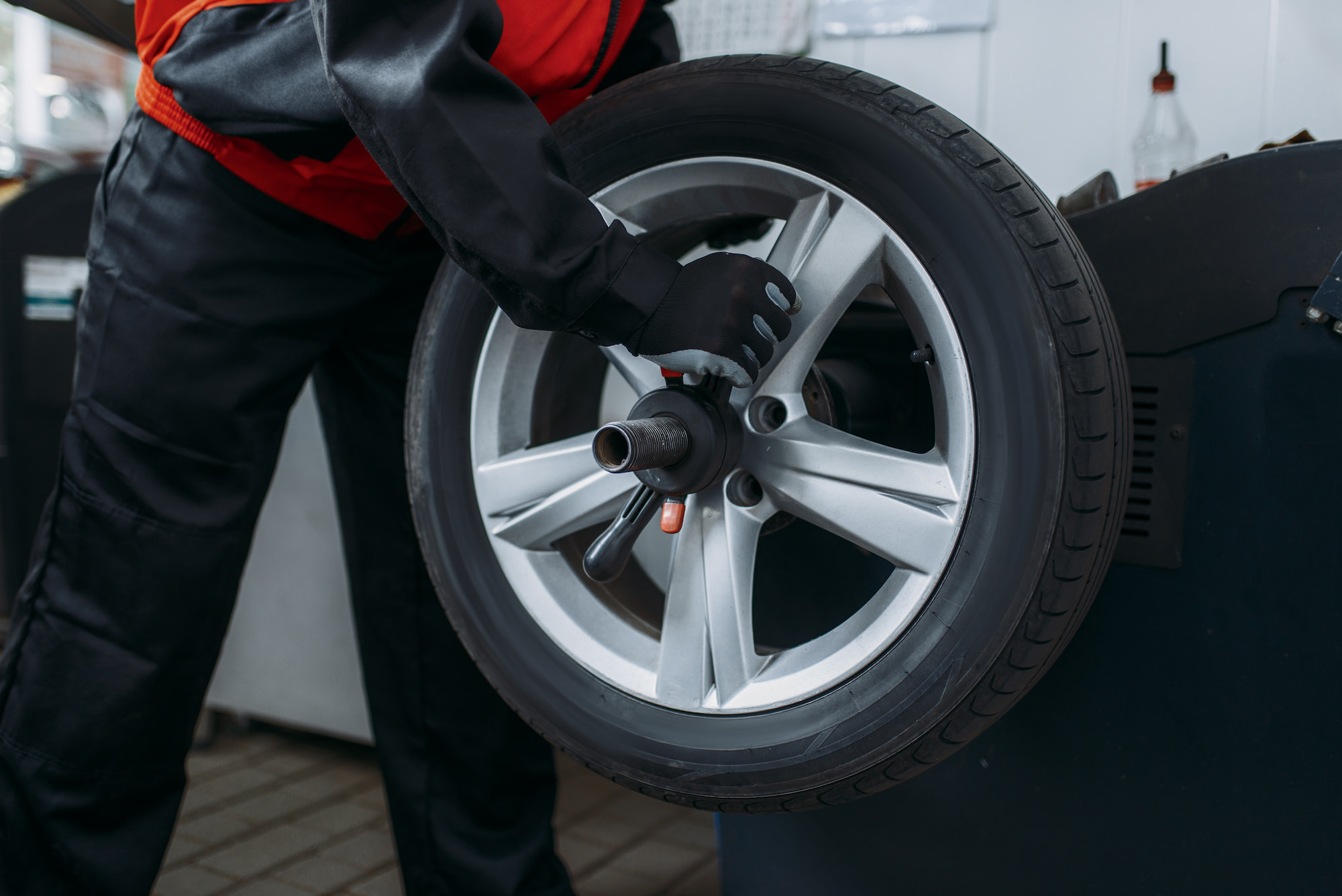 Technician adjusting wheel on tire balancing machine at auto repair shop in Fond du Lac, WI.