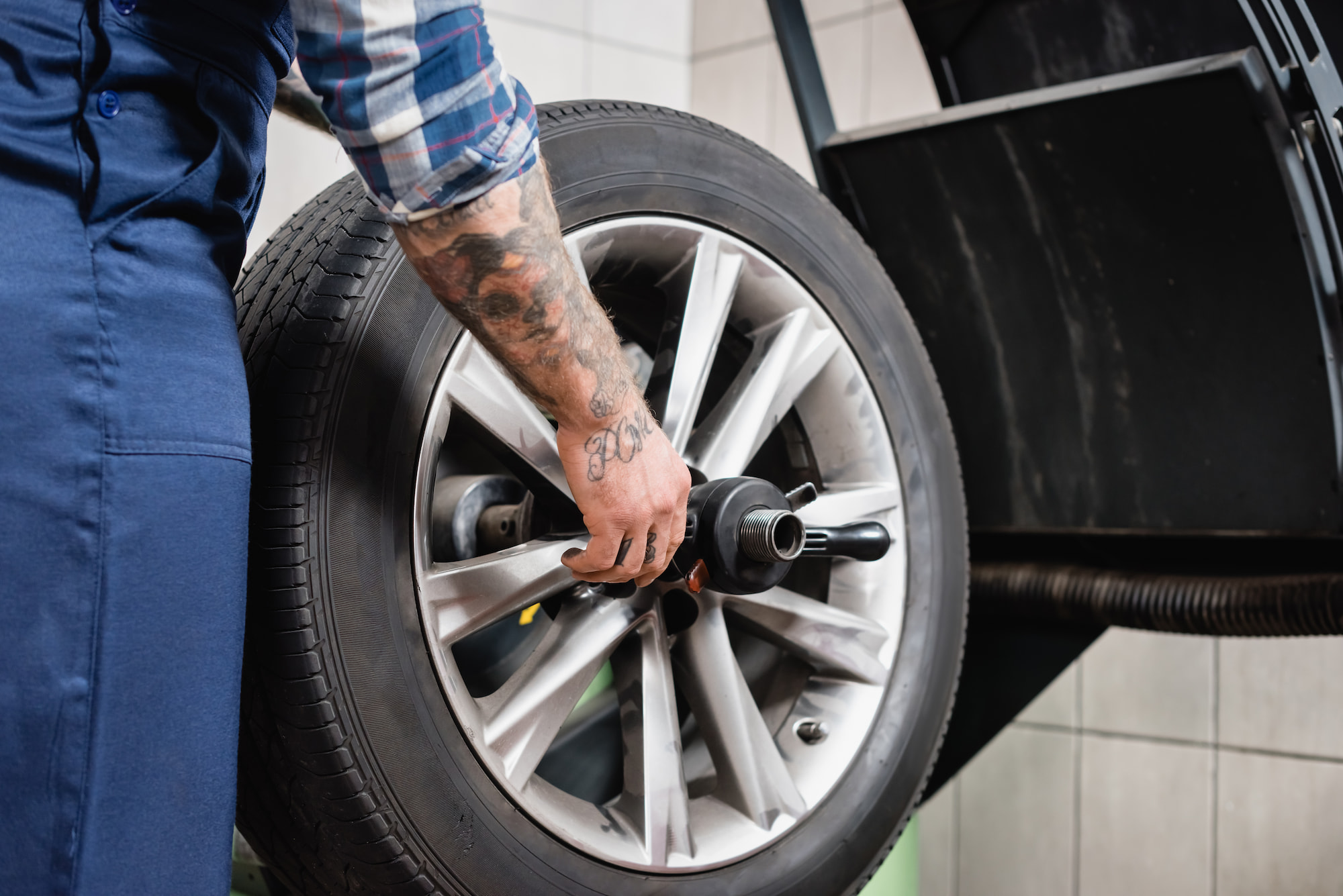 Technician securing alloy wheel on tire balancing machine at auto repair shop in Menasha, WI.